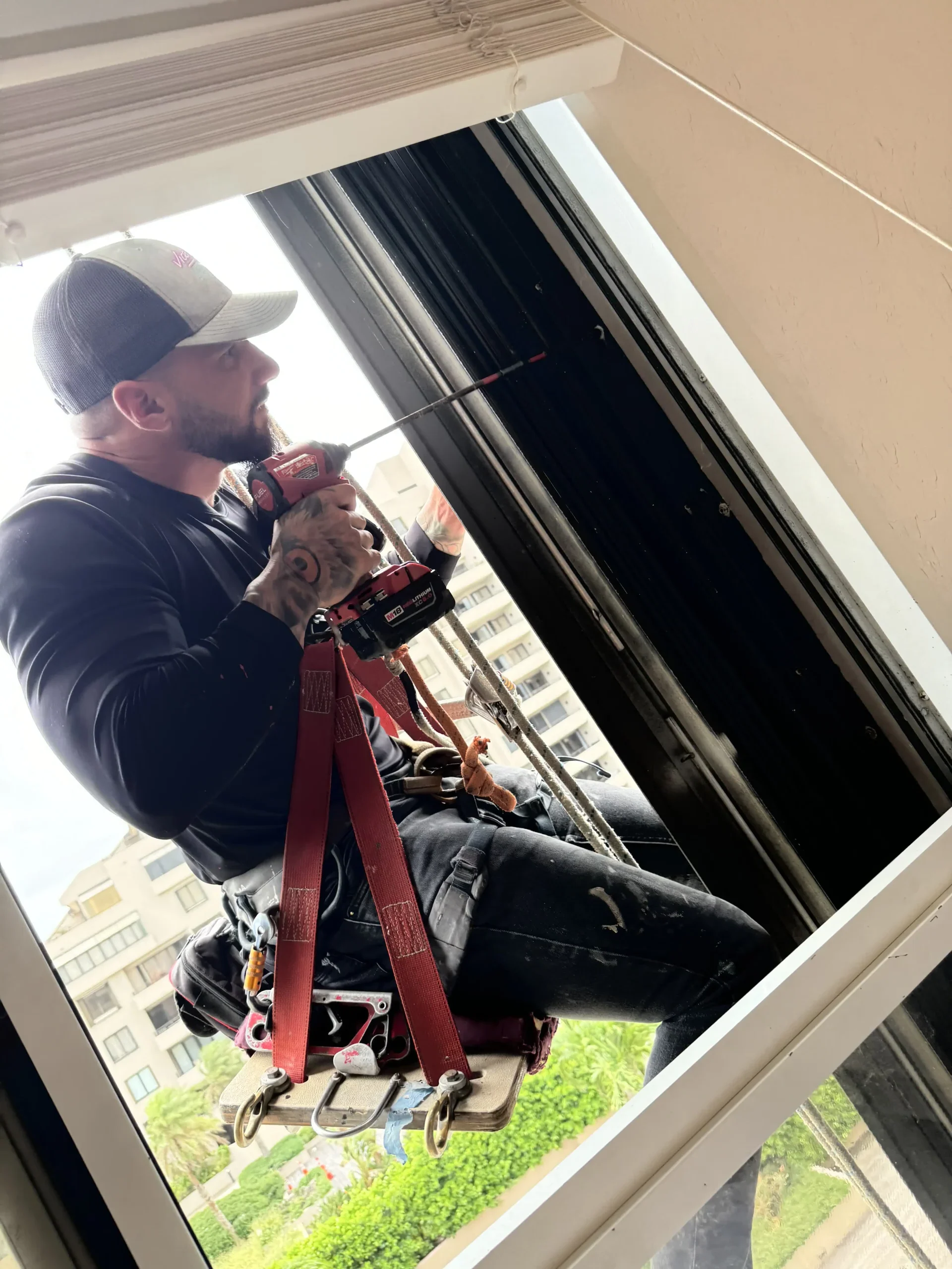 Installer on a bosun chair securing an impact window frame
